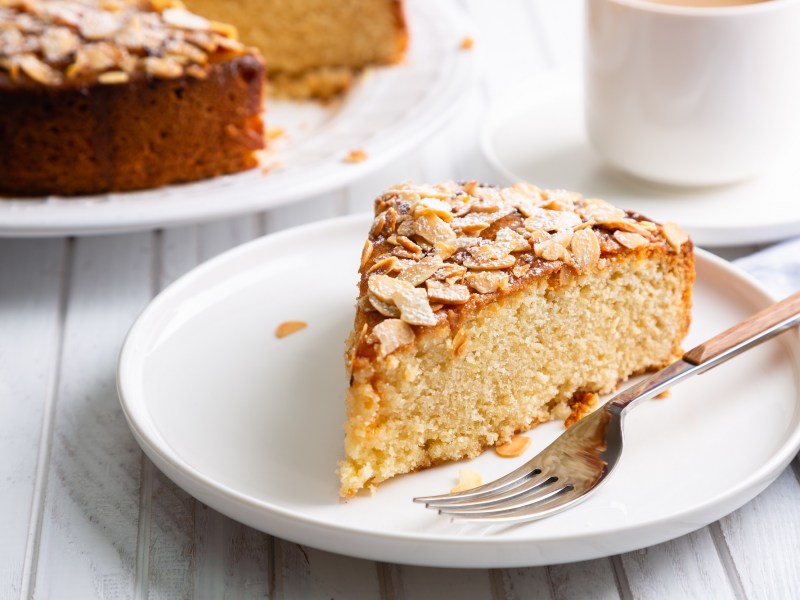 Ein Stück Blitzkuchen mit Mandeln auf einem weißen Teller