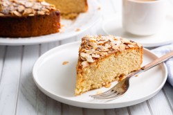 Ein Stück Blitzkuchen mit Mandeln auf einem weißen Teller