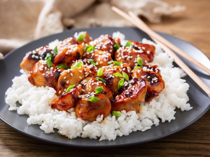 Chicken-Teryaki auf schwarzem Teller und Stäbchen