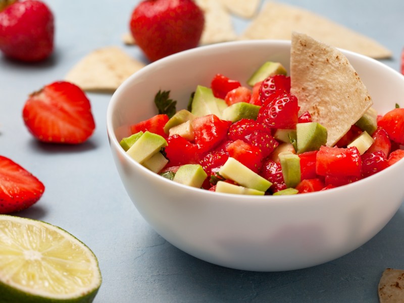 Erdbeer-Avocado-Salsa in einer weißen Schüssel. Dazu wird ein Tortilla-Chip serviert