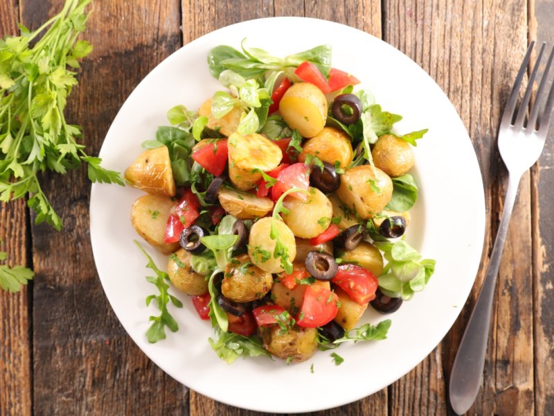 Ein Teller mit mediterranem Kartoffelsalat in der Draufsicht.