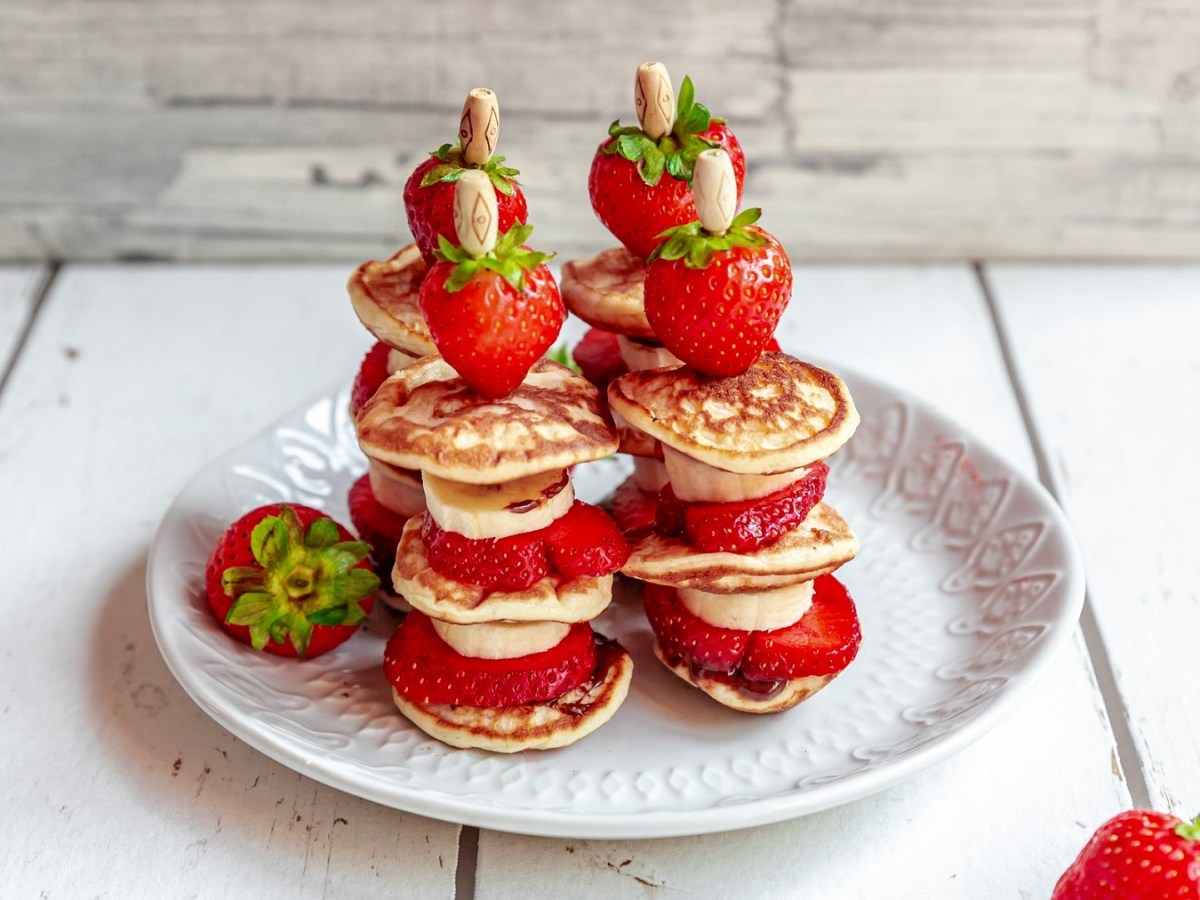 4 Pancake-Kebab-Spieße mit Bananen und Erdbeeren auf einem Teller