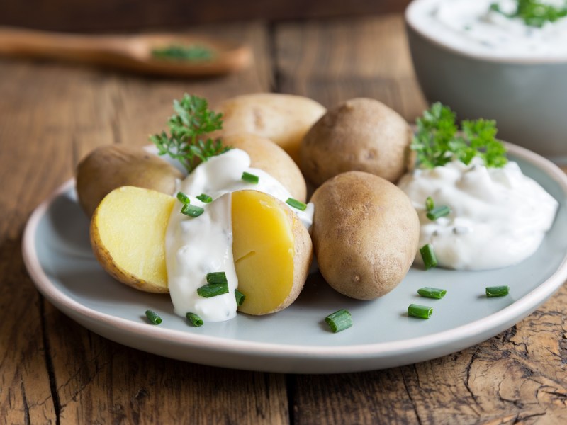 Ein Teller Pellkartoffeln mit Quark, dazu passt und Gurkensalat.