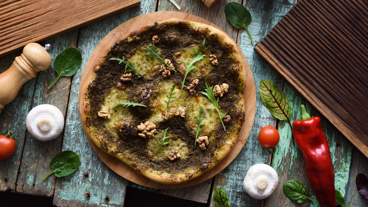 Pizza mit grünem Pesto und Walnüssen.