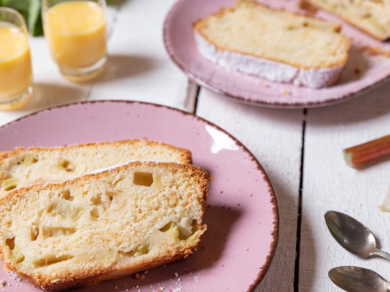 Zwei Stücke Rhabarber-Kastenkuchen auf einem rosa Teller.