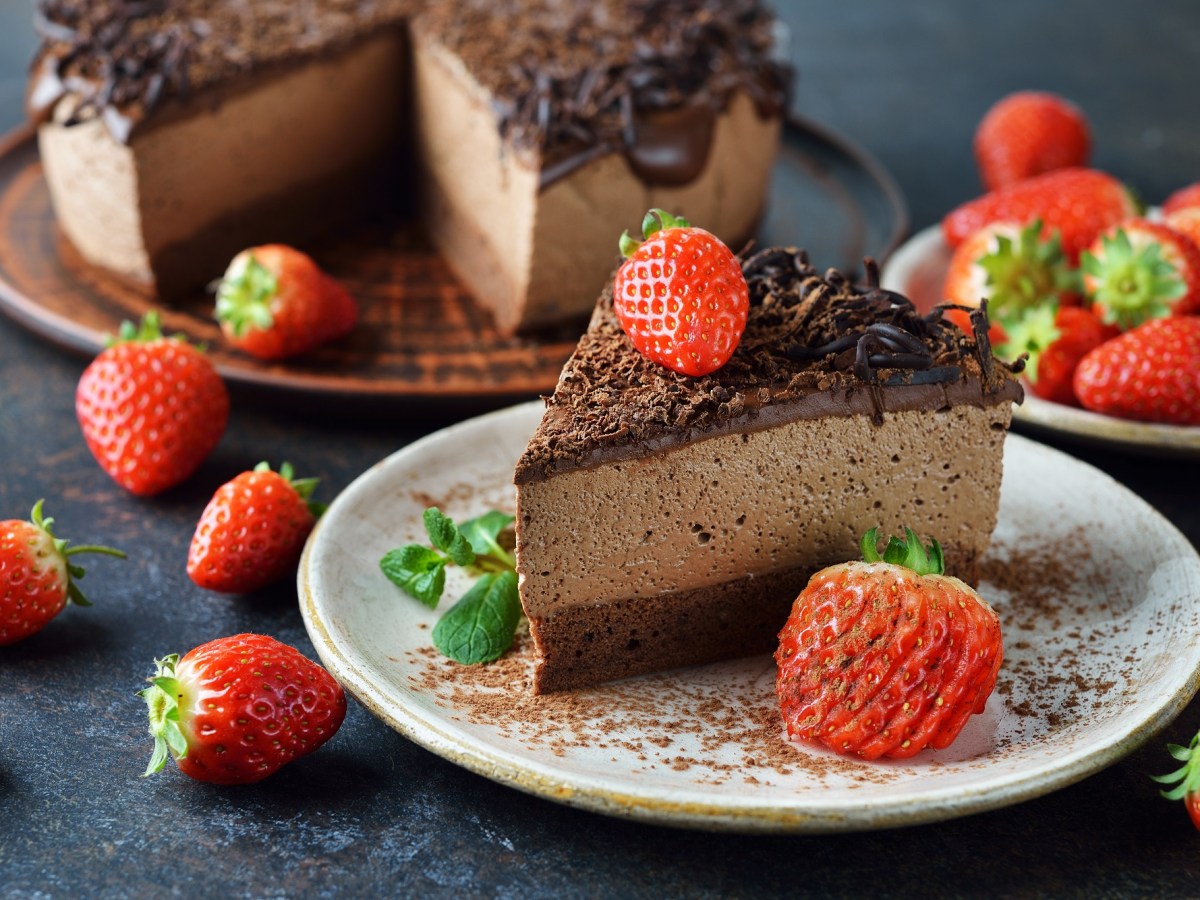 Ein Stück Schokomousse-Torte, garniert mit Erdbeeren, auf einem weißen Teller.