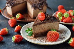 Ein Stück Schokomousse-Torte, garniert mit Erdbeeren, auf einem weißen Teller.