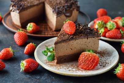 Ein Stück Schokomousse-Torte, garniert mit Erdbeeren, auf einem weißen Teller.