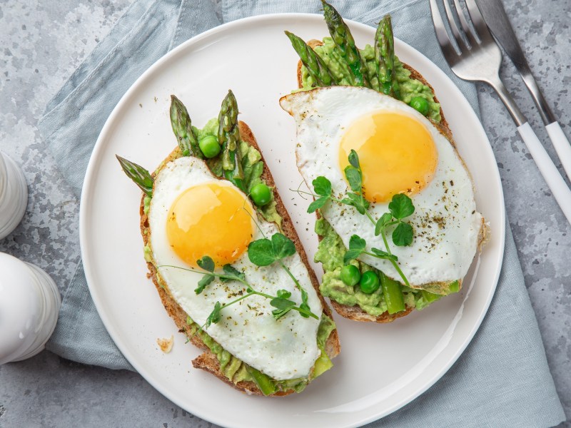 Spargel-Toast mit Spiegelei und Avocado auf einem Teller.