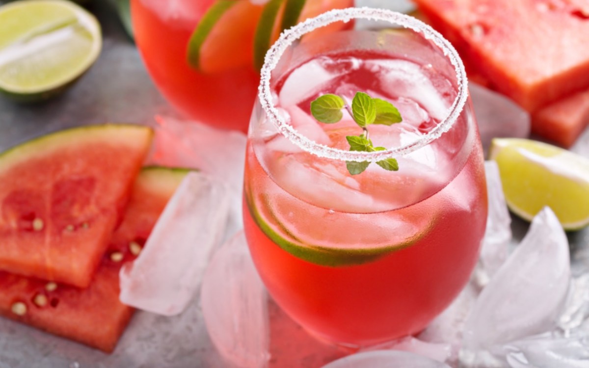 Ein Glas Watermelon Man. Drumherum liegen Limetten, Eiswürfel und frische Wassermelone.