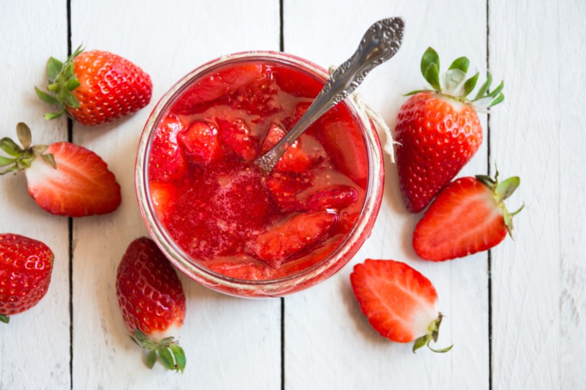 Wie bleibt Erdbeermarmekade rot: Erdbeermarmelade im Glas in der Draufsicht. Daneben frische Erdbeeren.