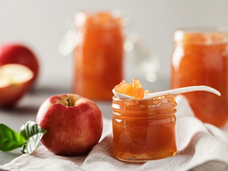 Ein Schälchen mit Apfel-Salzkaramell-Marmelade. Dahinter liegen frische Äpfel.