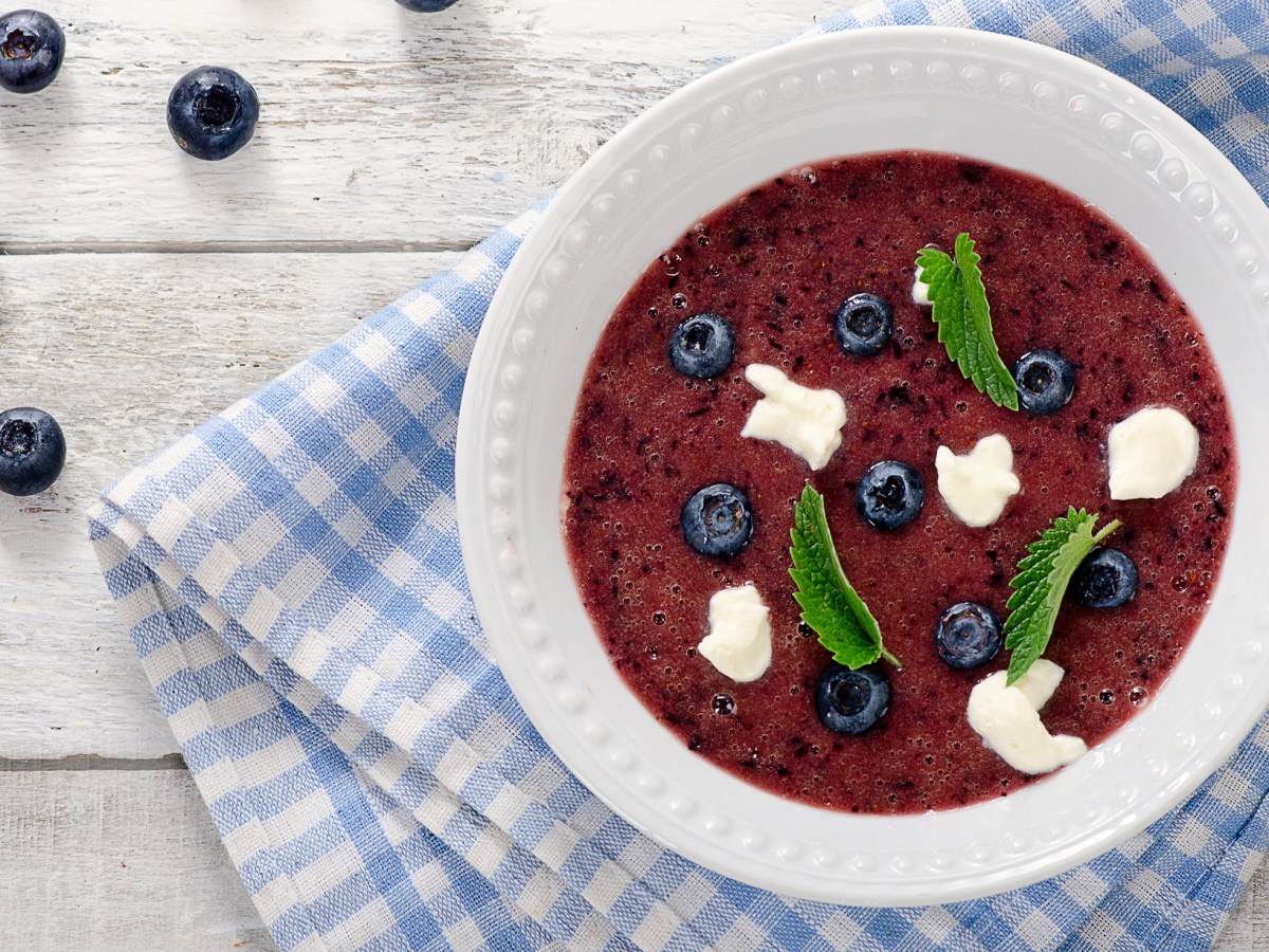 Teller mit schwedischer Blaubeersuppe und blau-weiß-kariertem Tischtuch