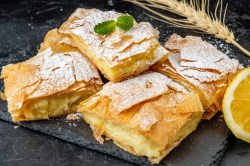 Einige Stücke Bougatsa serviert auf einer Schiefertafel.