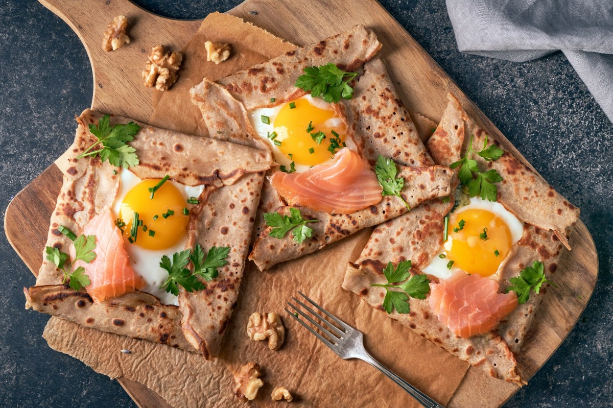 Bretonische Galettes mit Ei und Lachs auf einem Brett.