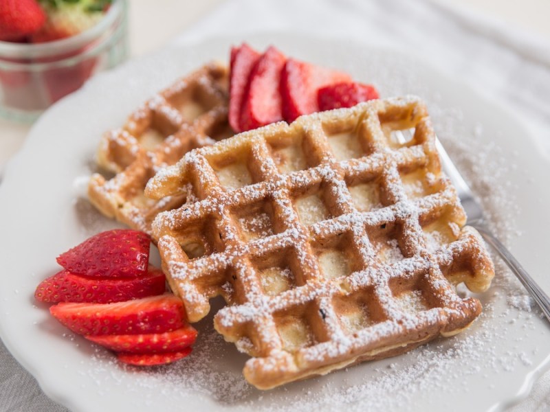 Dinkel-Waffeln mit Erdbeeren auf weißem Teller.