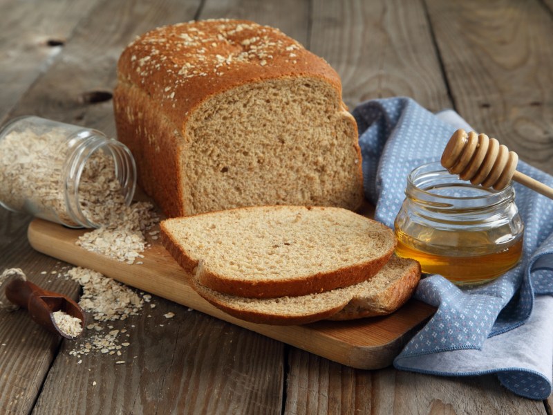 Ein angeschnittenes Honigbrot auf einem Holzbrett.