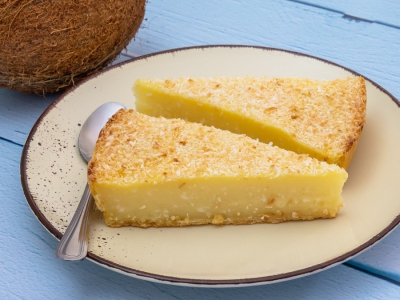 Joghurt-Kokos-Kuchen auf hellem Teller und blauen Tisch.