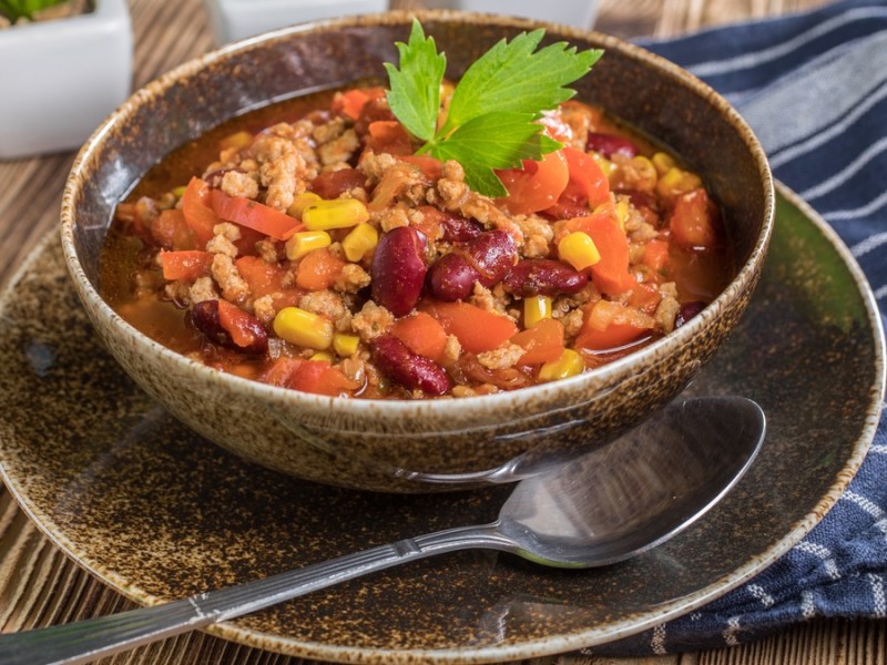 Mitternachtssuppe in dunkler Schale und blauem Geschirrtuch.