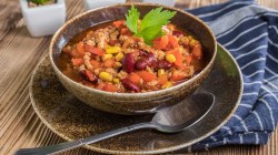 Mitternachtssuppe in dunkler Schale und blauem Geschirrtuch.