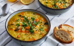 Eine Schüssel Reissuppe. Daneben liegen 2 Stücke Brot.