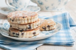 Welsh Cakes übereinandergestapelt auf einem Teller. Dieser steht auf einer blau-weiß-karierten Serviette.