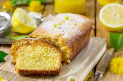 Ein angeschnittener Zitronenkuchen mit Kamille auf einem dekorierten Tisch.