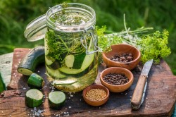 Ein Glas eingelegte Zucchini mit Gewürzen und Messer