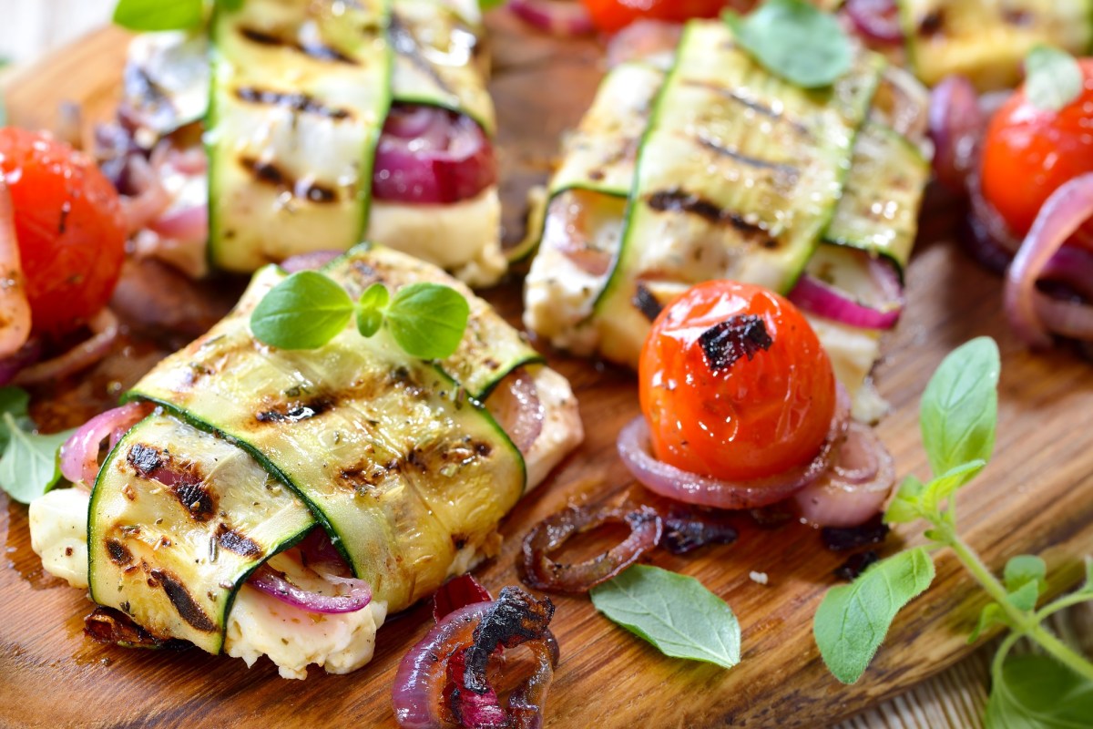 Holzbrett mit Feta-Zucchini-Päckchen vom Grill