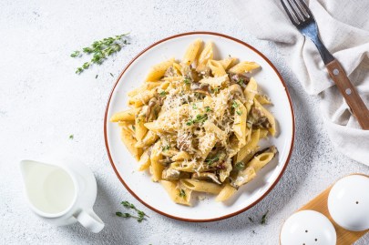 Nudeln mit Steinpilz-Sahneso&szlig;e auf einem hellen Teller. Daneben befinden sich die Zutaten.