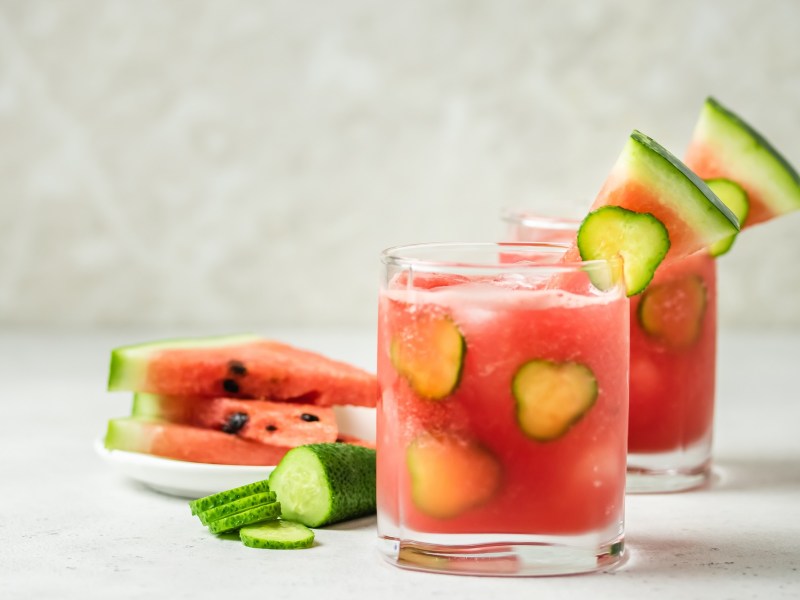 Zwei Gläser Wassermelonen-Mojito, geschnittene Melone daneben