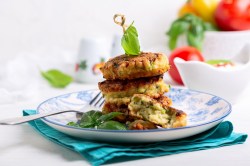 Zucchinipuffer mit Feta gestapelt auf einem Teller.