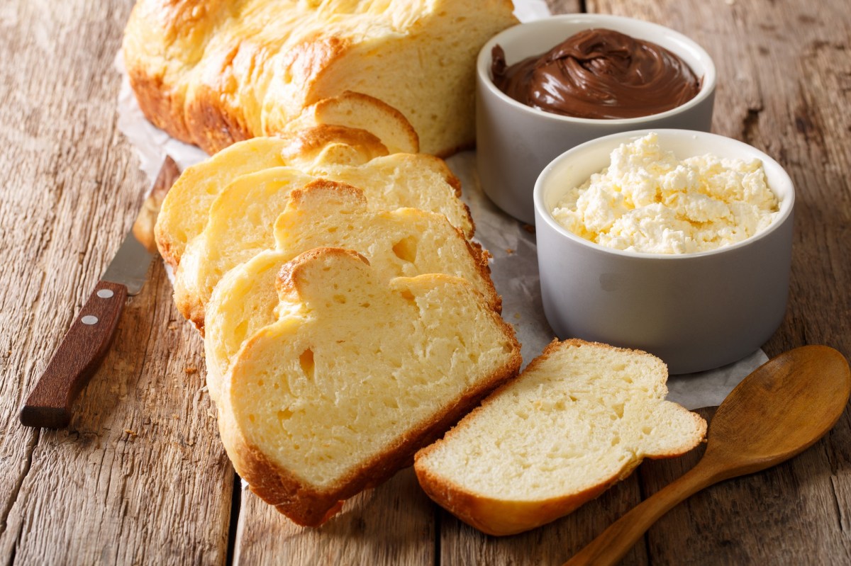 angeschnittenes Mascarpone-Brioche auf einem Holzbrett, Schokocreme daneben