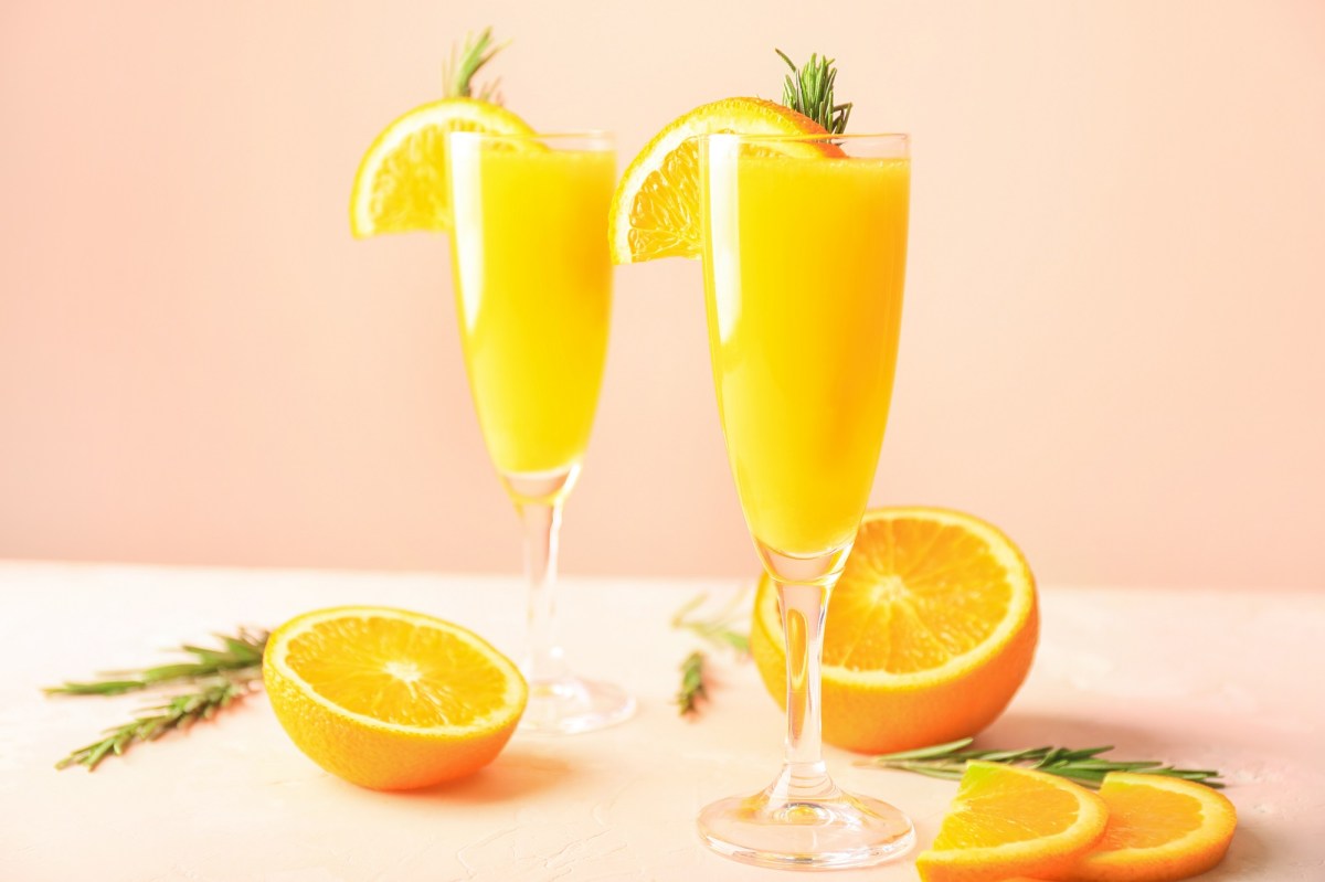 Zwei Mimosa Drinks auf einem Tisch, angeschnittene Orangen daneben.