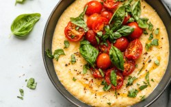 Eine Schüssel mit Polenta mit Tomaten und Basilikum in der Draufsicht.