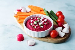 Schälchen mit Rote-Bete-Feta-Aufstrich und Gemüsesticks daneben.