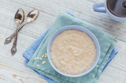 Schottischer Porridge in einer hellblauen Schüssel, daneben ligeen zwei Löffel.