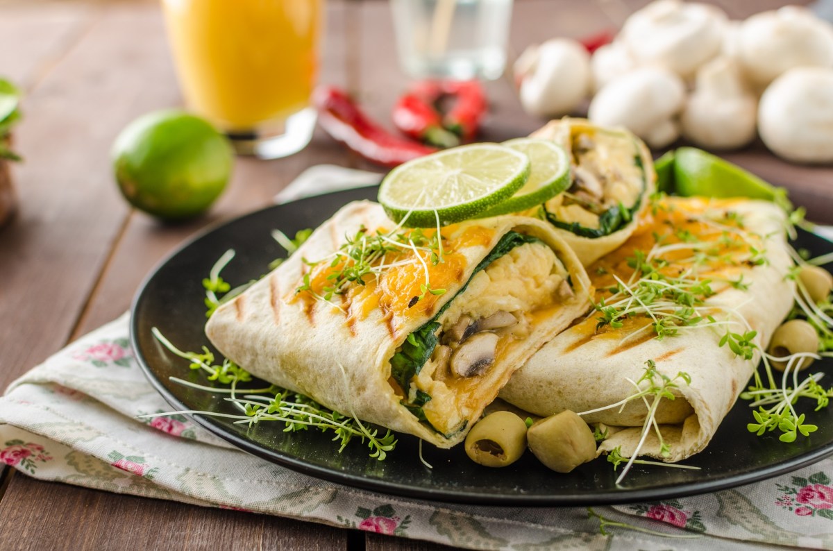 Frühstücksburrito mit Ei und Champignons auf einem Teller.