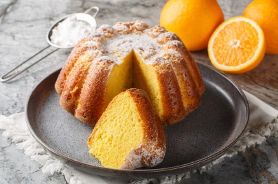 Marokkanischer Orangenkuchen Meskouta auf einem Anrichteteller. Von dem Kuchen wurde ein Stück abgeschnitten.