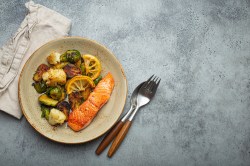 Ofenlachs mit Rosenkohl auf einem Teller. Daneben liegt Besteck.