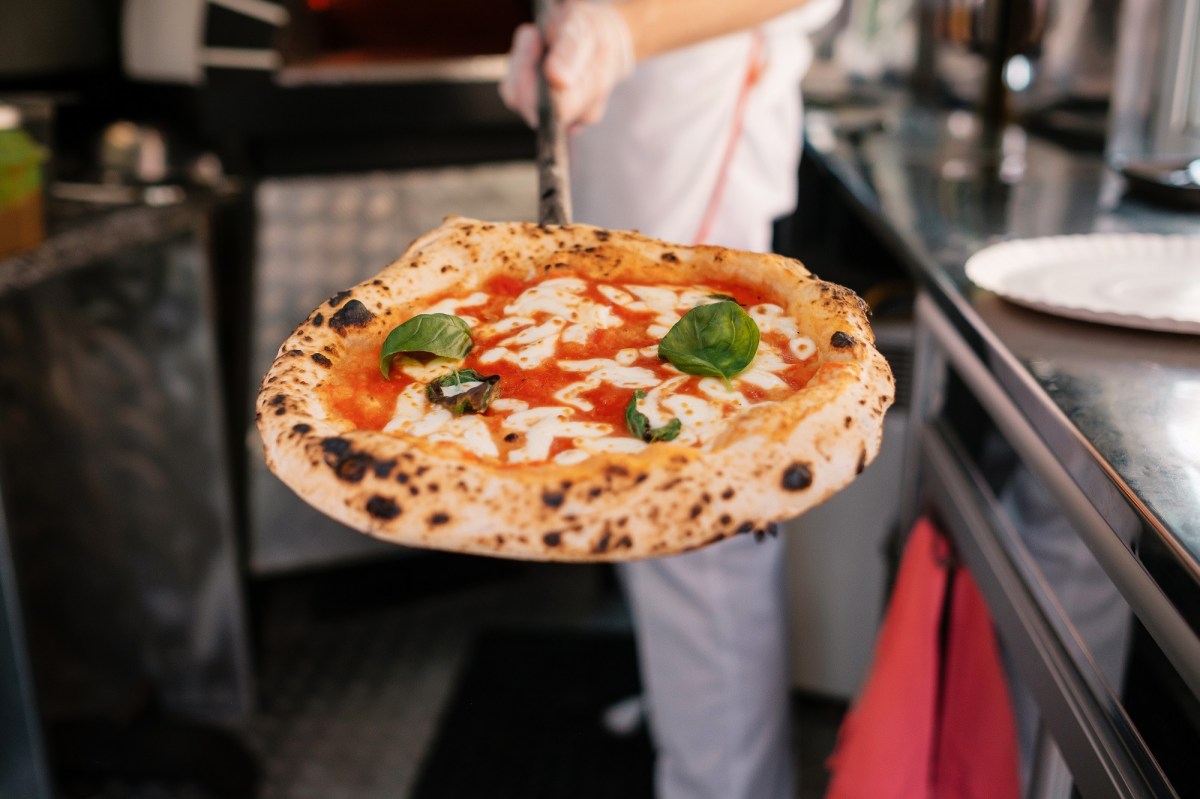 Perfekte Pizza: Ein Pizzabäcker präsentiert eine fertige Pizza.