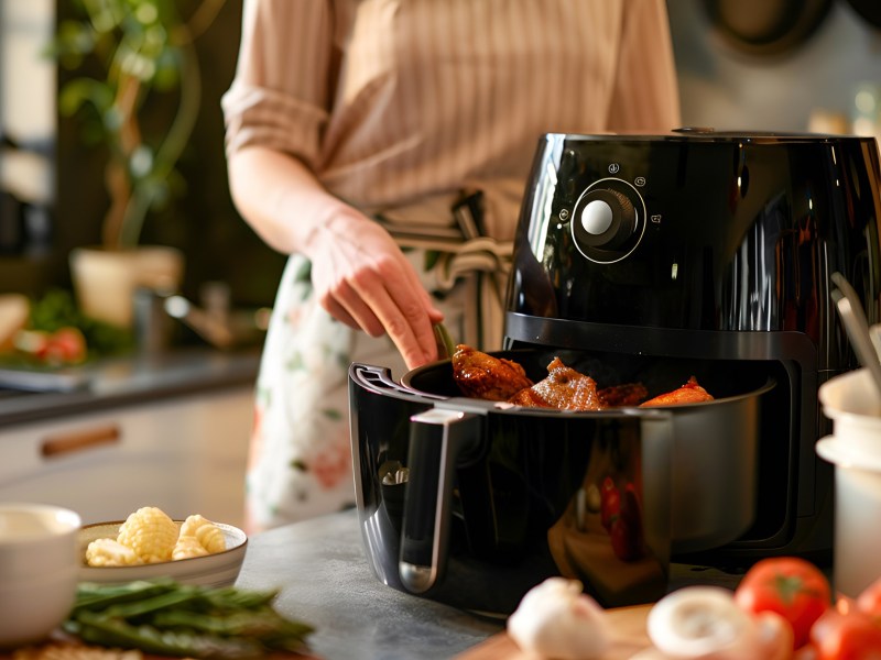 Heißluftfritteuse vorheizen: Eine Frau legt Zutaten in einen Airfryer.