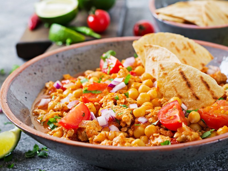 Eine Servierschüssel mit Chili con Carne mit Kürbis und Tortillas.