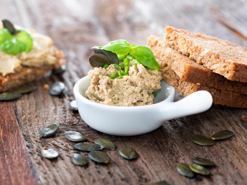 Schale mit Kürbiskern-Aufstrich mit Brot und Kürbiskernen