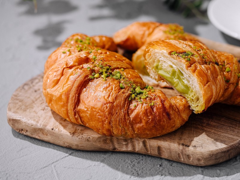 Schnelle Pistazien-Croissants auf einem Brett, bestreut mit Pistazien.