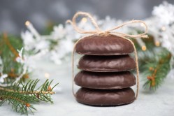 Rezept für Lebkuchen: 4 Nürnberger Lebkuchen gestapelt und mit einem Band zusammengebunden, dahinter Weihnachtsdeko.