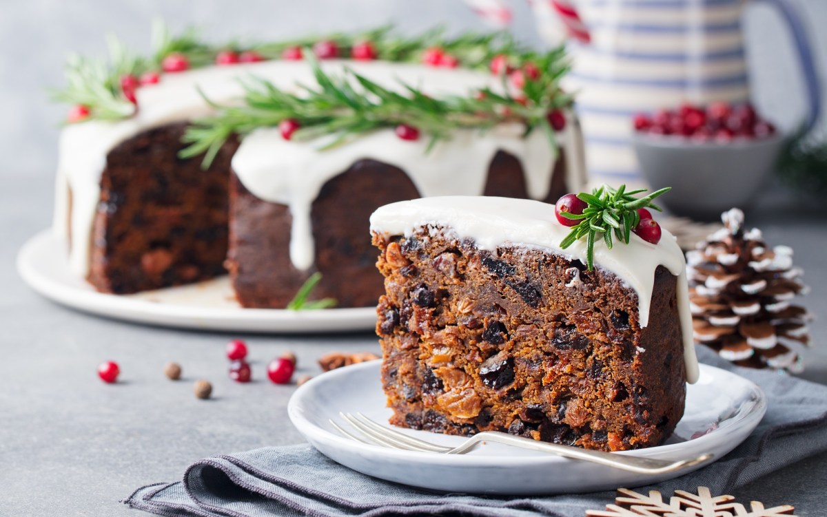 Ein Stück Englischer Weihnachtskuchen. Im Hintergrund ist der Rest des Kuchens zu sehen.