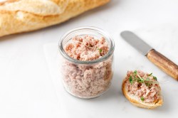 Gänse-Rillettes in einem Glas, einiges davon wurde bereits auf ein Brot gestrichen.