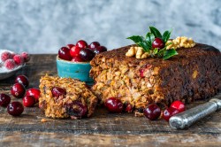 Ein angeschnittener Nussbraten, drumherum Zutaten wie frische Cranberrys.