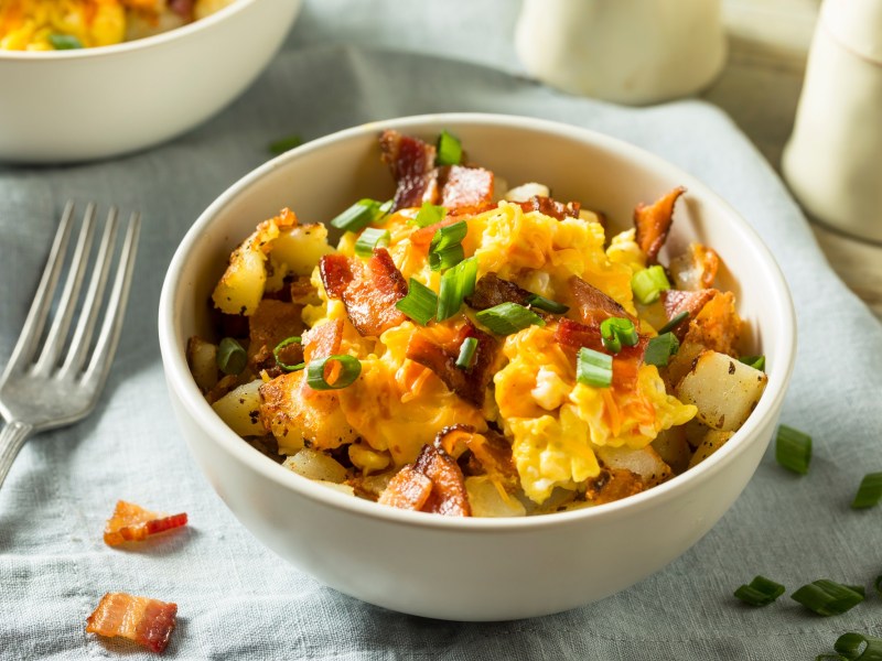 Rührei-Kartoffel-Bowl, mit Speck bestreut.